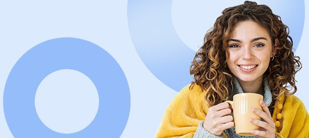 Kobieta pod kocem z kubkiem